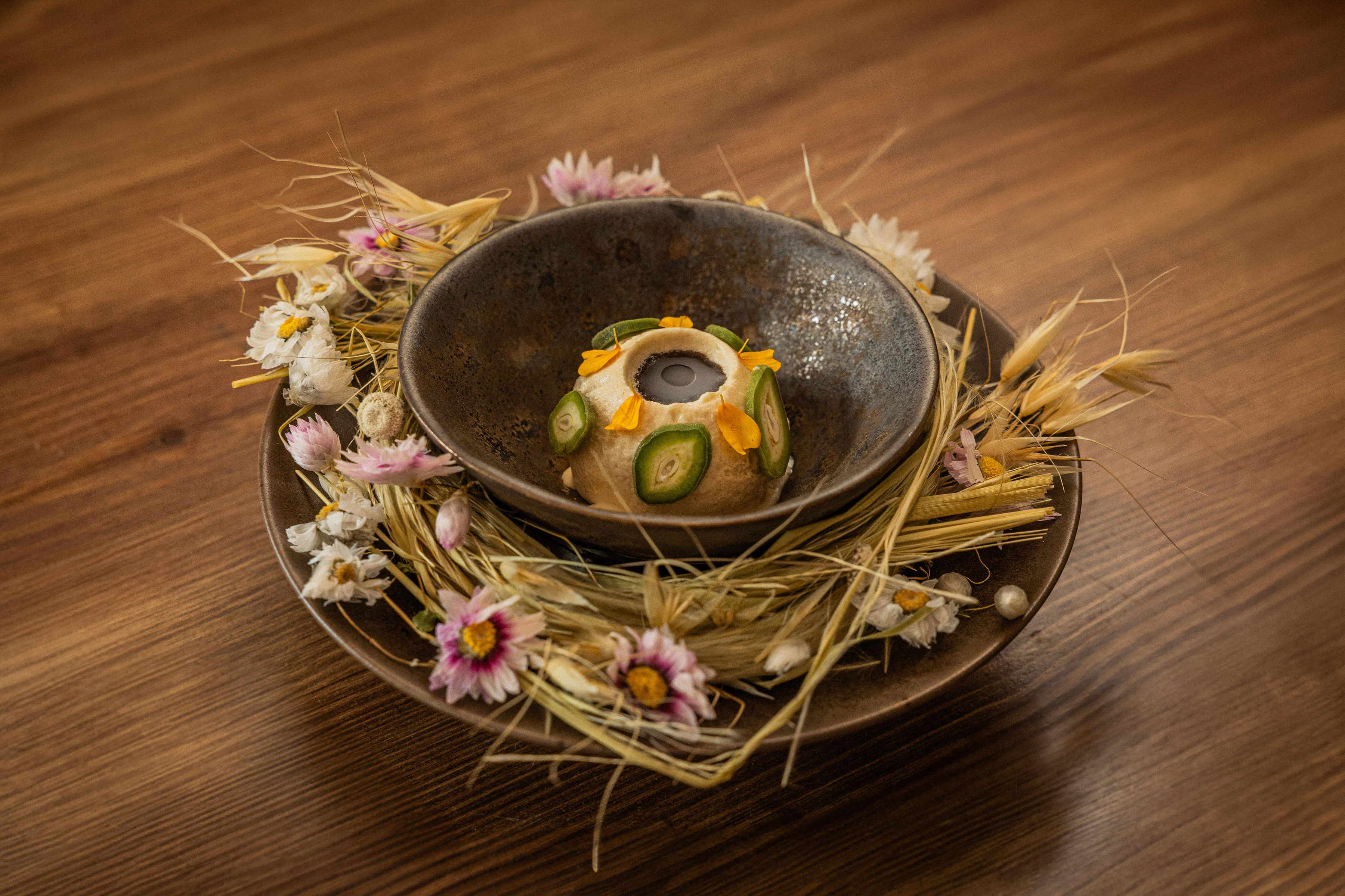 Halva with pickled almonds in a bowl, decorated with dried flowers and wheat.