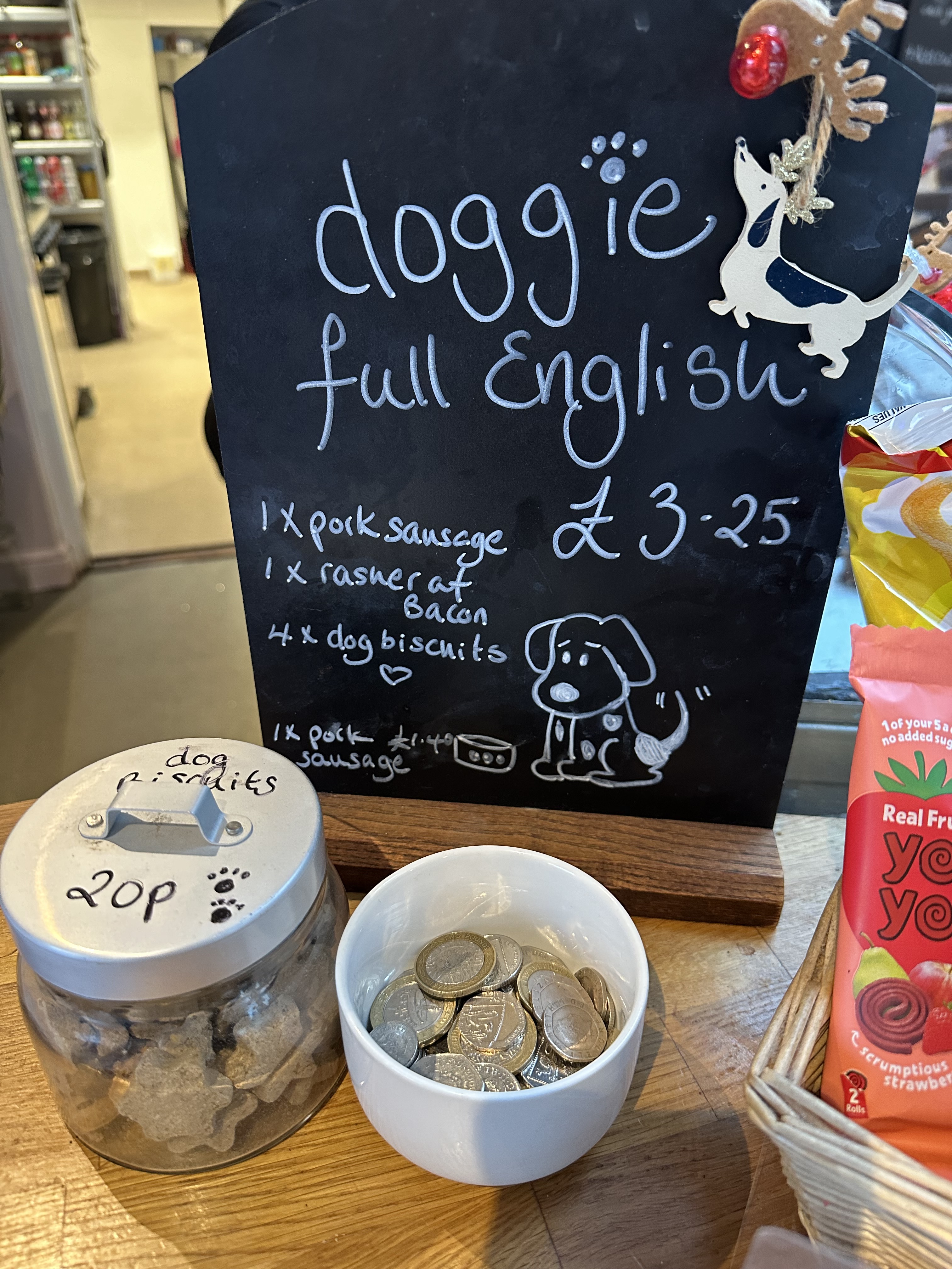 Menu board for a doggie full English breakfast with a jar of dog biscuits and bowl coins.